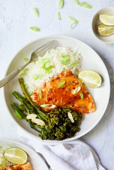 Sheet Pan Thai Baked Fish with Broccolini on white plate with rice garnished with scallions.