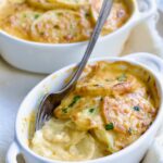 Two oval dishes of Au Gratin Potatoes for Two with fork digging into one.