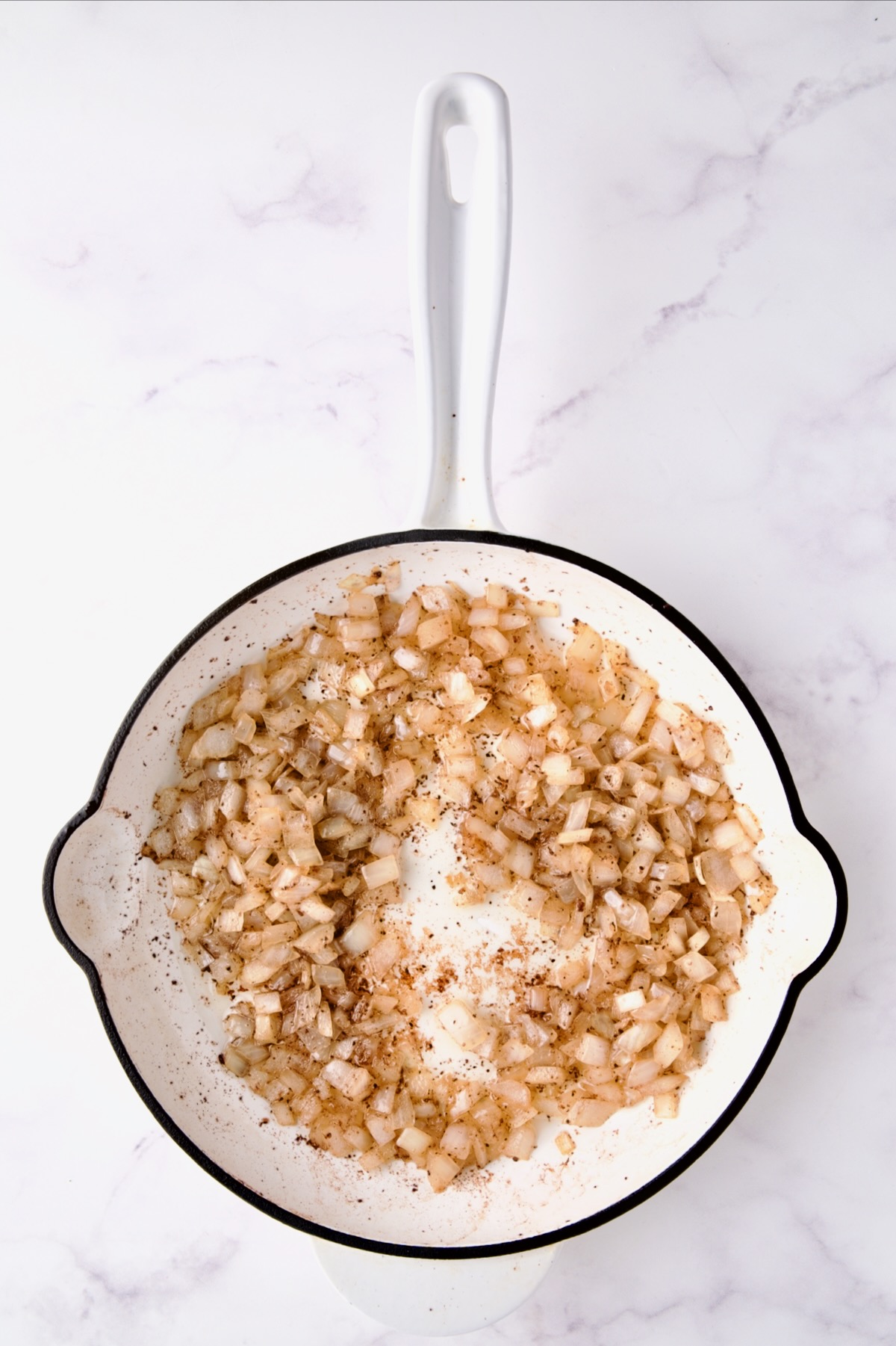 Cooked onions in white enamel cast iron skillet.
