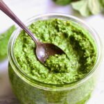 Radish Greens Pesto in glass jar with spoon scooping some up.