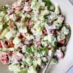 Cucumber Tomato Feta Salad in round ceramic bowl with serving spoon.