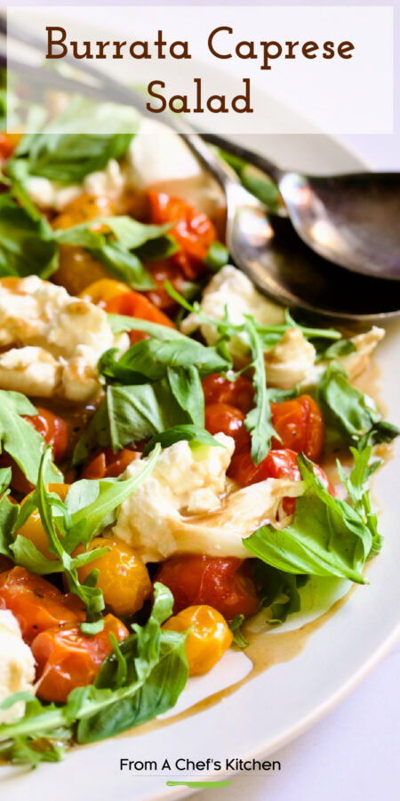 Pinterest graphic for Burrata Caprese Salad showing it on a white platter with serving utensils.