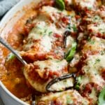 Serving spoon scooping one Eggplant Rollatini from oval baking dish.
