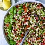 Black-Eyed Pea Salad in white bowl with lemon wedges and cilantro in bowls.
