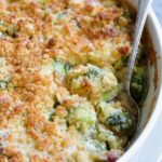 Brussels Sprouts Gratin in oval baking dish with spoon scooping some up.