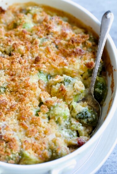 Brussels Sprouts Gratin in oval baking dish with spoon scooping some up.