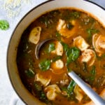 Sausage Spinach Tortellini Soup in white Dutch oven with soup ladle.