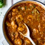 Finished Best Shrimp Creole in white enamel cast iron skillet with serving spoon.