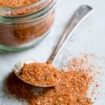 Spoon of Blackening Seasoning spilling over onto surface with jar in the background.