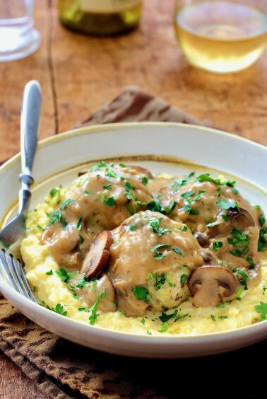 Chicken Meatballs Marsala with Parmesan Polenta in white bowl with fork.