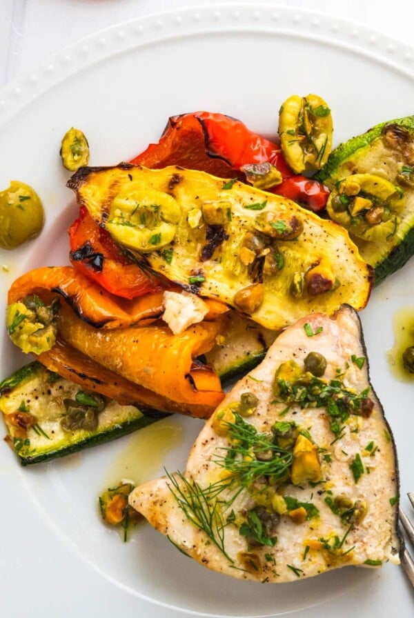 Swordfish steaks on white plate with olive relish.
