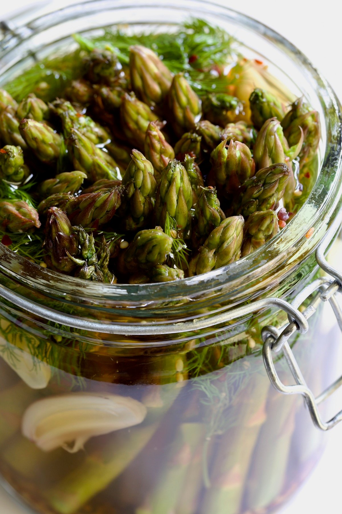 Asparagus with brine poured over it in glass jar.