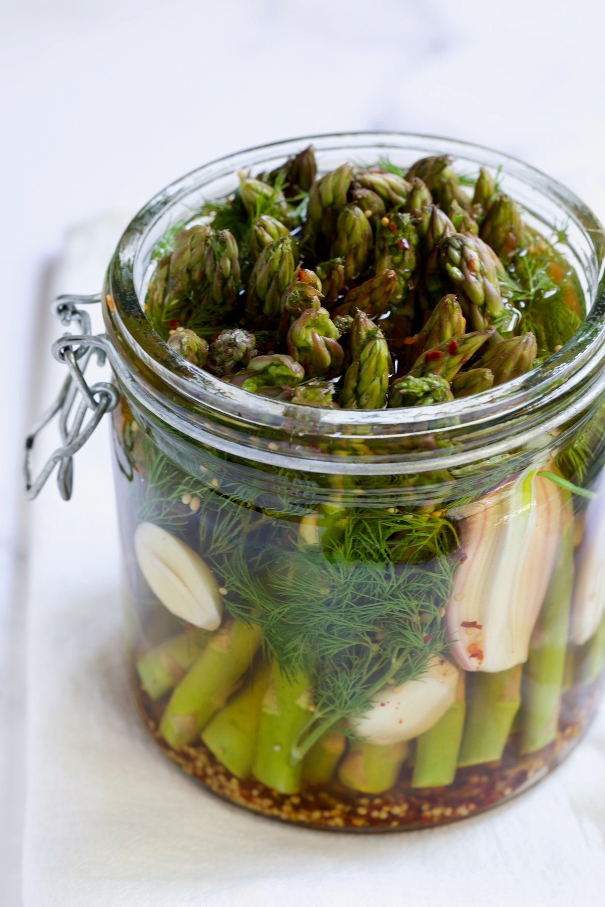 Pickled Asparagus with brine poured over it in glass jar.