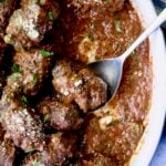 Beef Braciole in oval white serving dish with serving spoon.