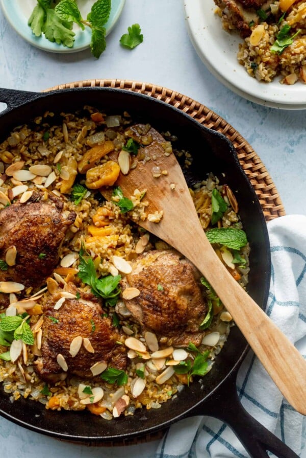 Four Lebanese Chicken Thighs with Freekeh and Apricots in cast iron skillet.