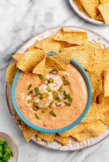 Creamy Shrimp Salsa Dip in bright blue bowl on platter with tortilla chips.