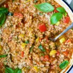 Barley Vegetable Risotto in white enameled cast iron pan garnished with fresh basil.