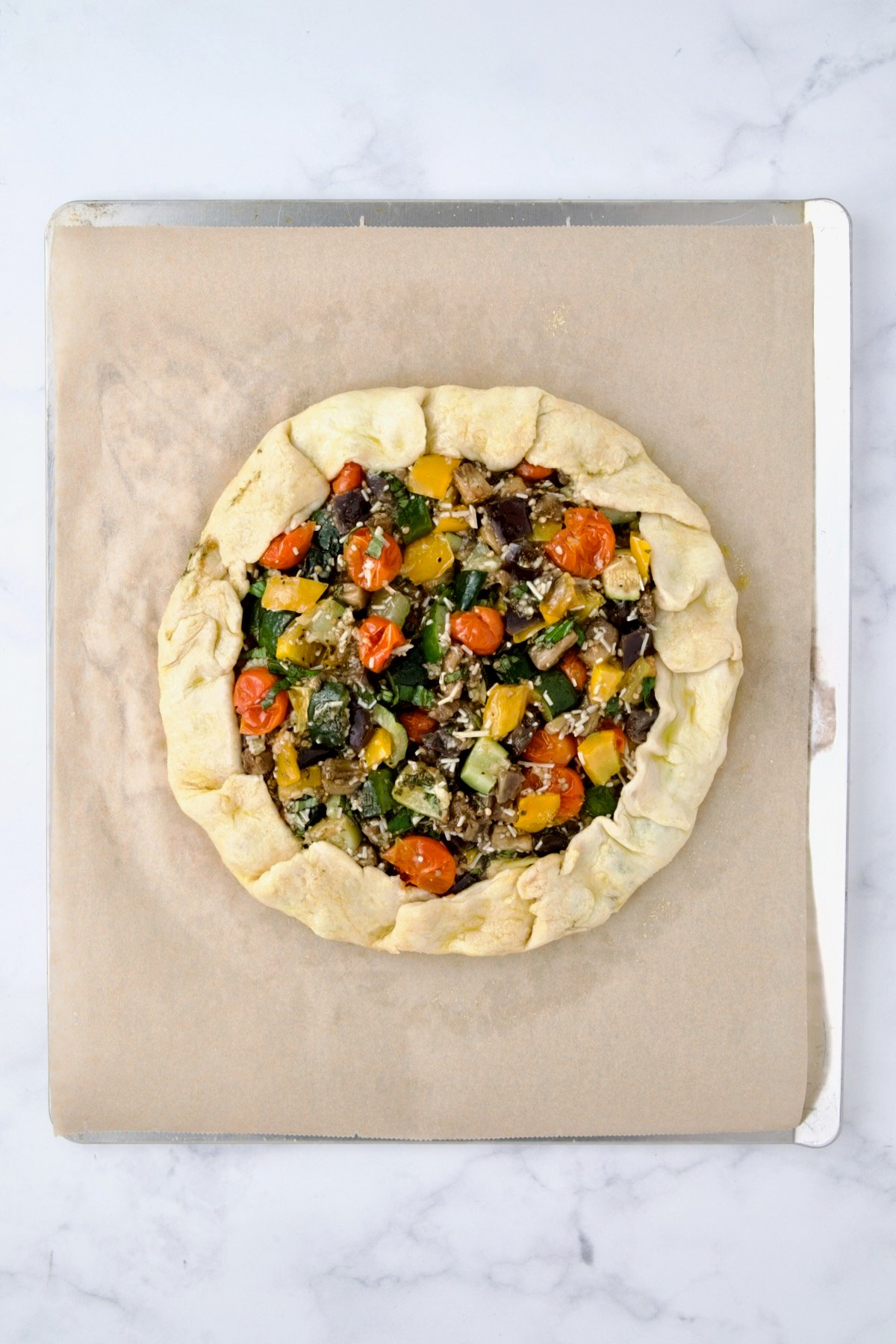 Fully assembled galette on parchment paper on cookie sheet before being baked.