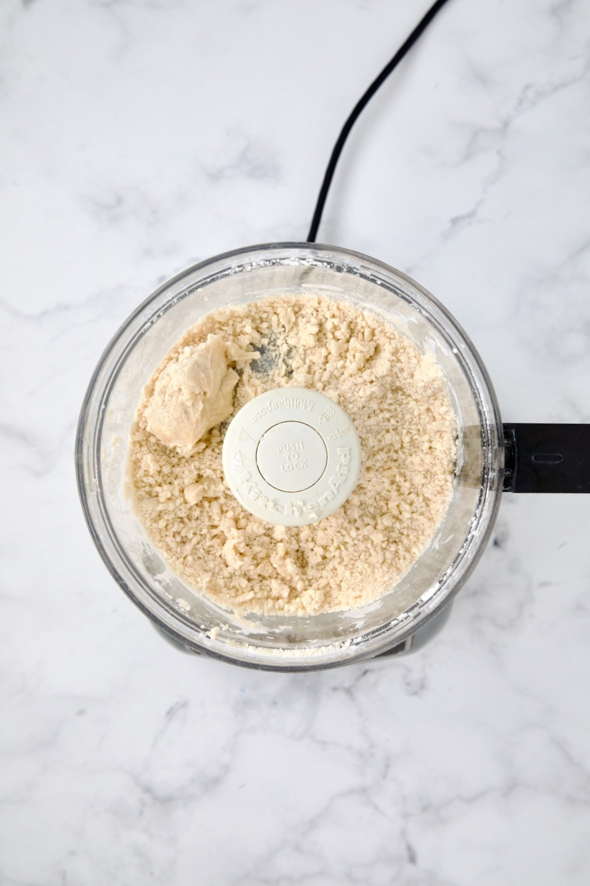Ingredients for galette dough in food processor holding together after ice water is added.