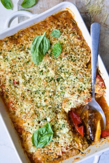 Summer Vegetable Parmigiana in white baking dish with serving spoon scooping some up.
