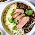 Four slices of Cuban-Style Pork Tenderloin with Black Beans and rice in white bowl.