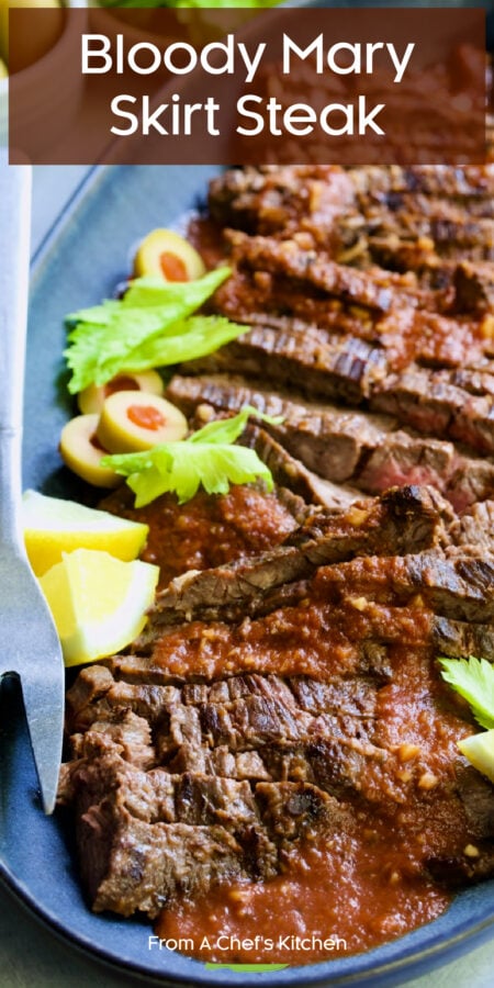 Pinterest graphic for Bloody Mary Skirt Steak showing it on a blue platter garnished with lemon wedges, celery leaves and sliced green olives.