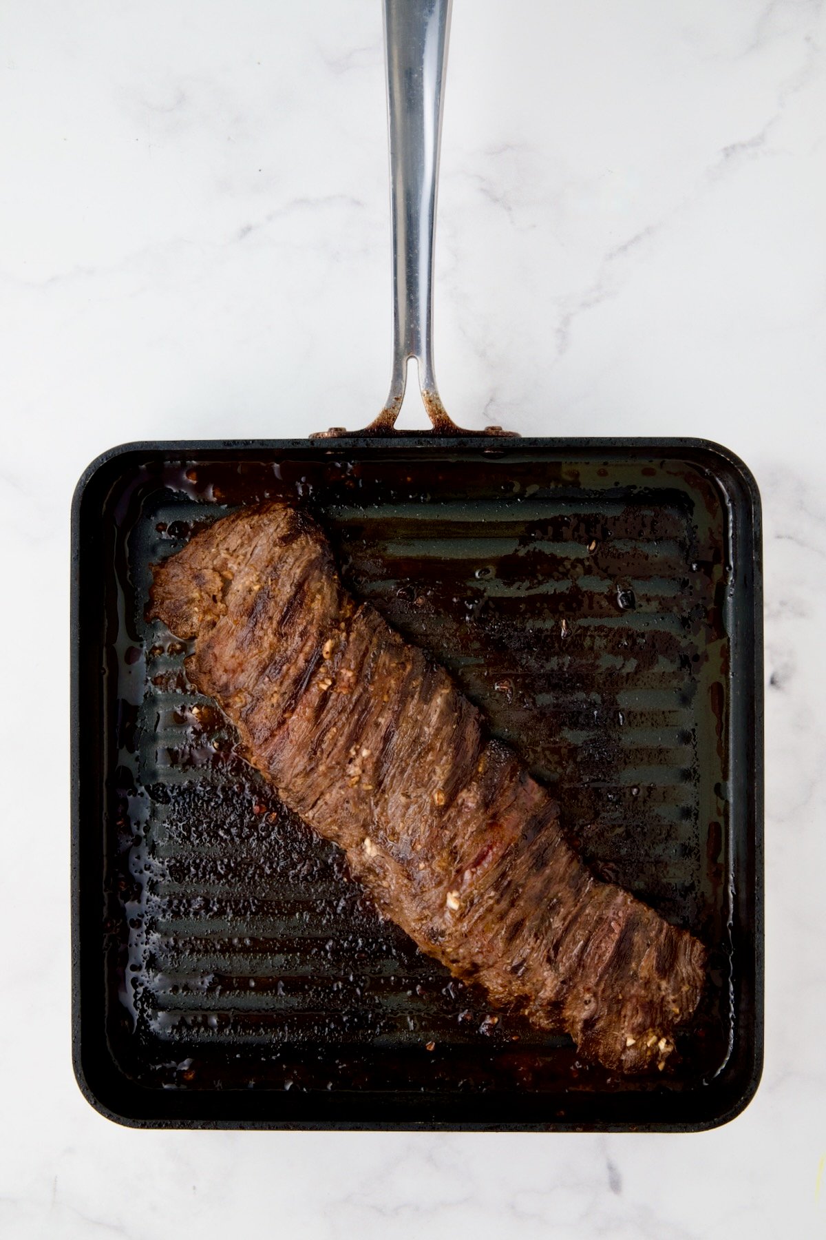 Grilled skirt steak on square grill pan.