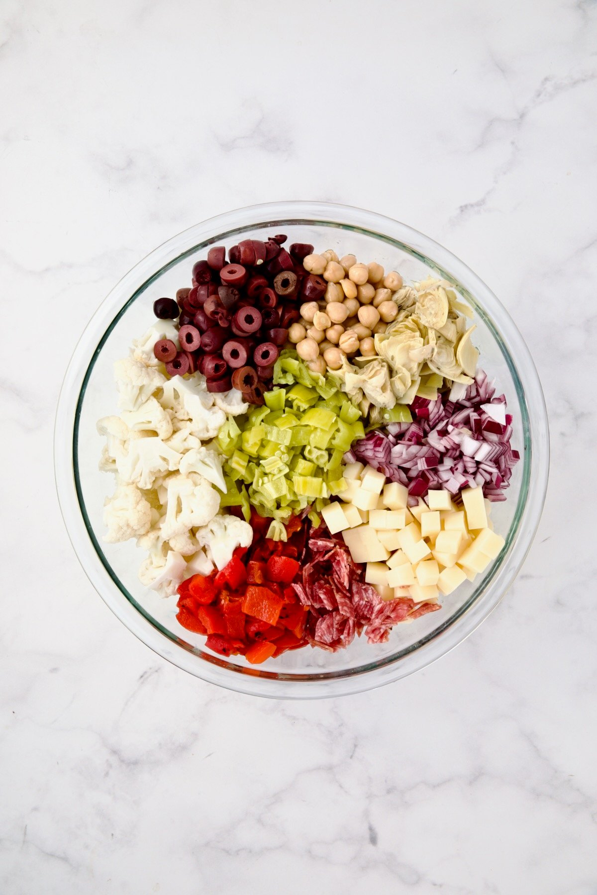 Ingredients for Cauliflower Antipasto Salad in glass bowl before being stirred together.