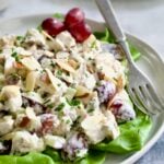 Chicken Salad with Herbs, Almonds and Grapes on lettuce on white plate.
