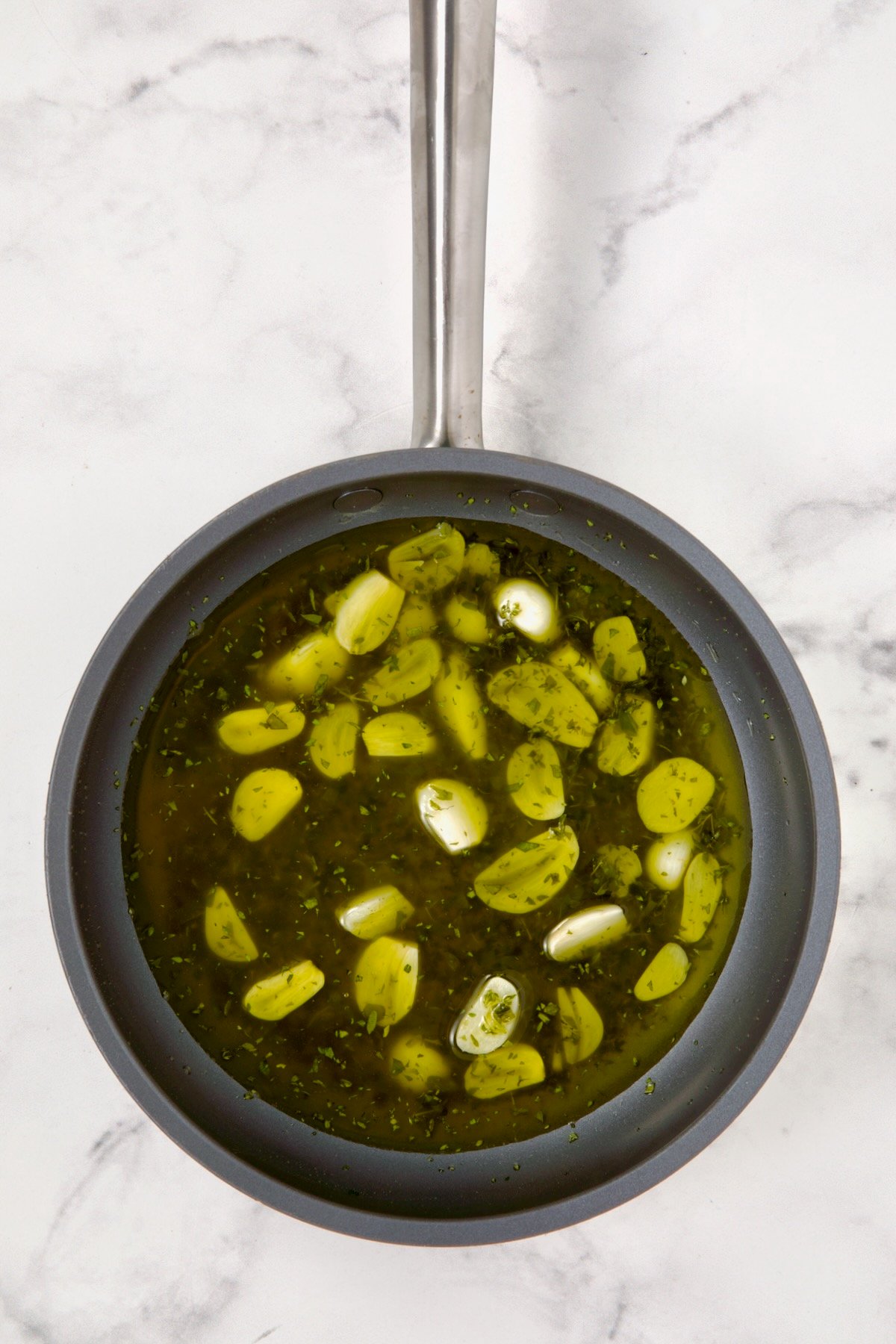 Sliced garlic and herbs in nonstick skillet.