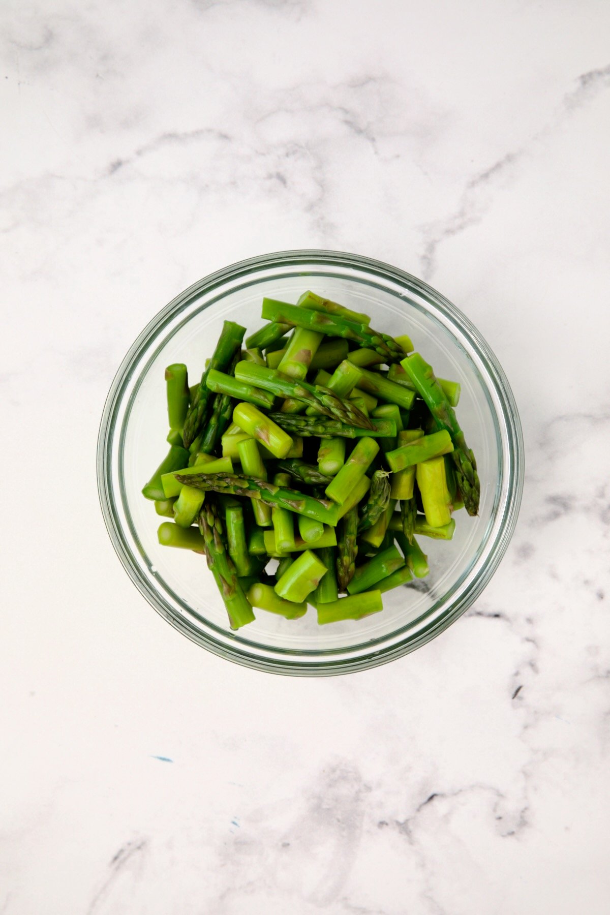 Asparagus pieces in glass bowl after being blanched.