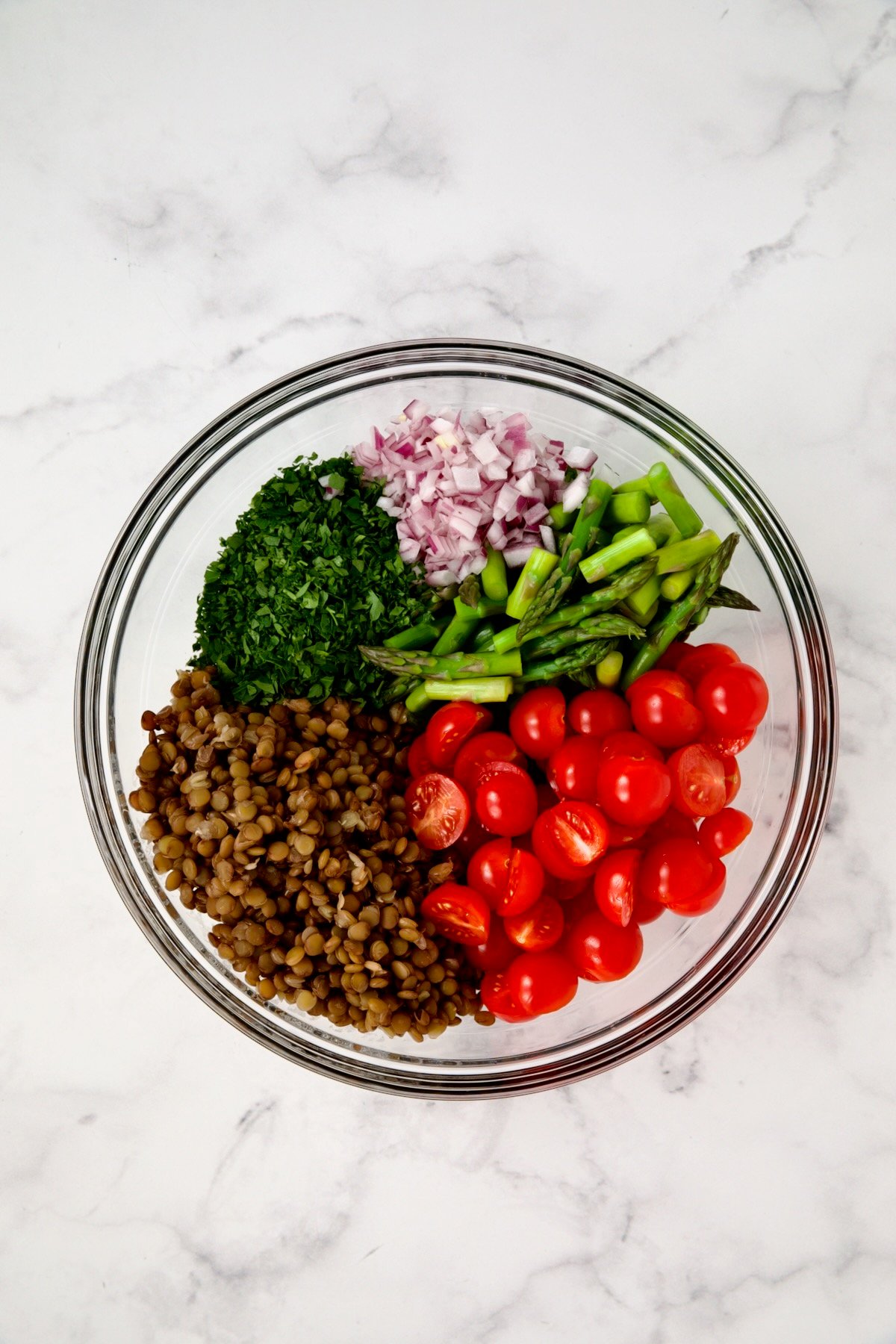 Ingredients for Lemony Lentil Salad with Asparagus and Tomatoes in glass bowl before being combined.