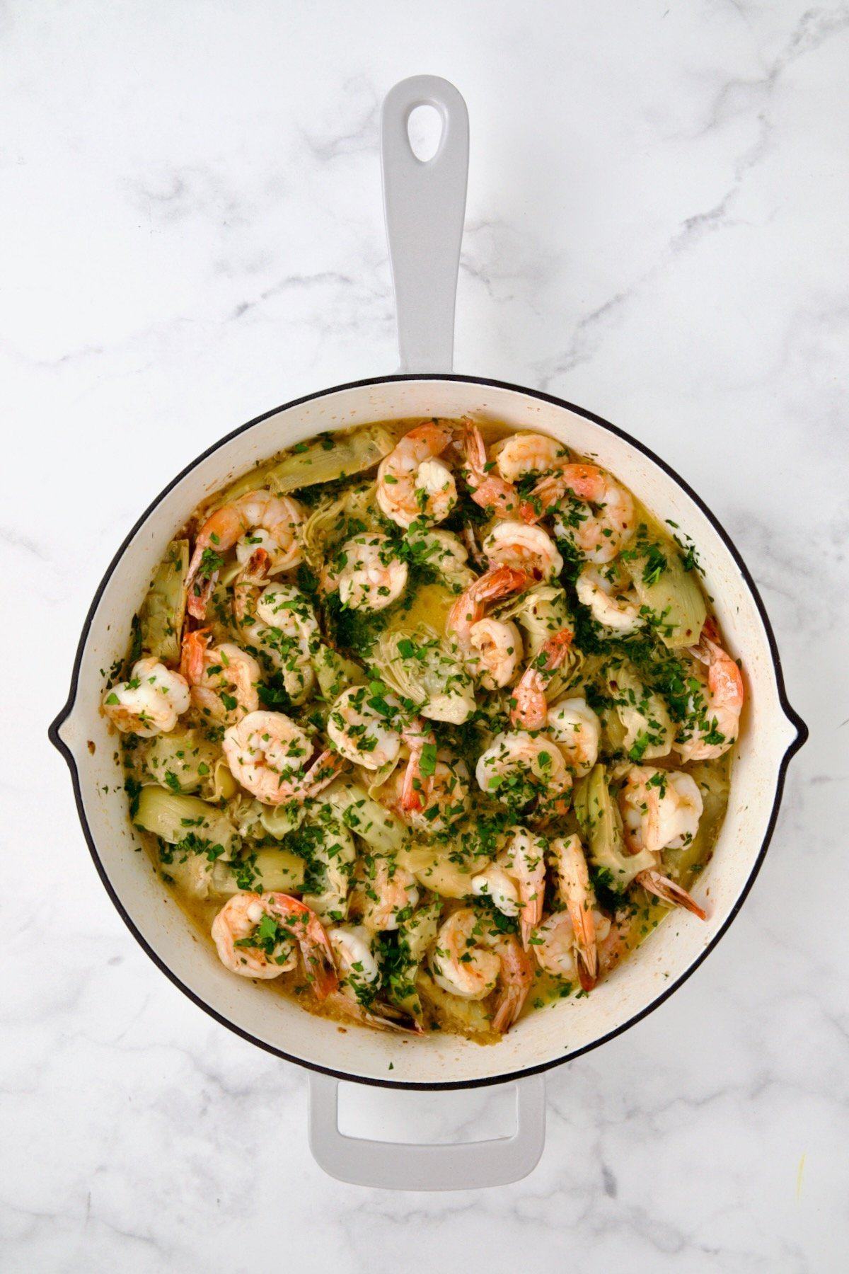 Finished Shrimp Scampi with Artichokes in white enamel cast iron pan.