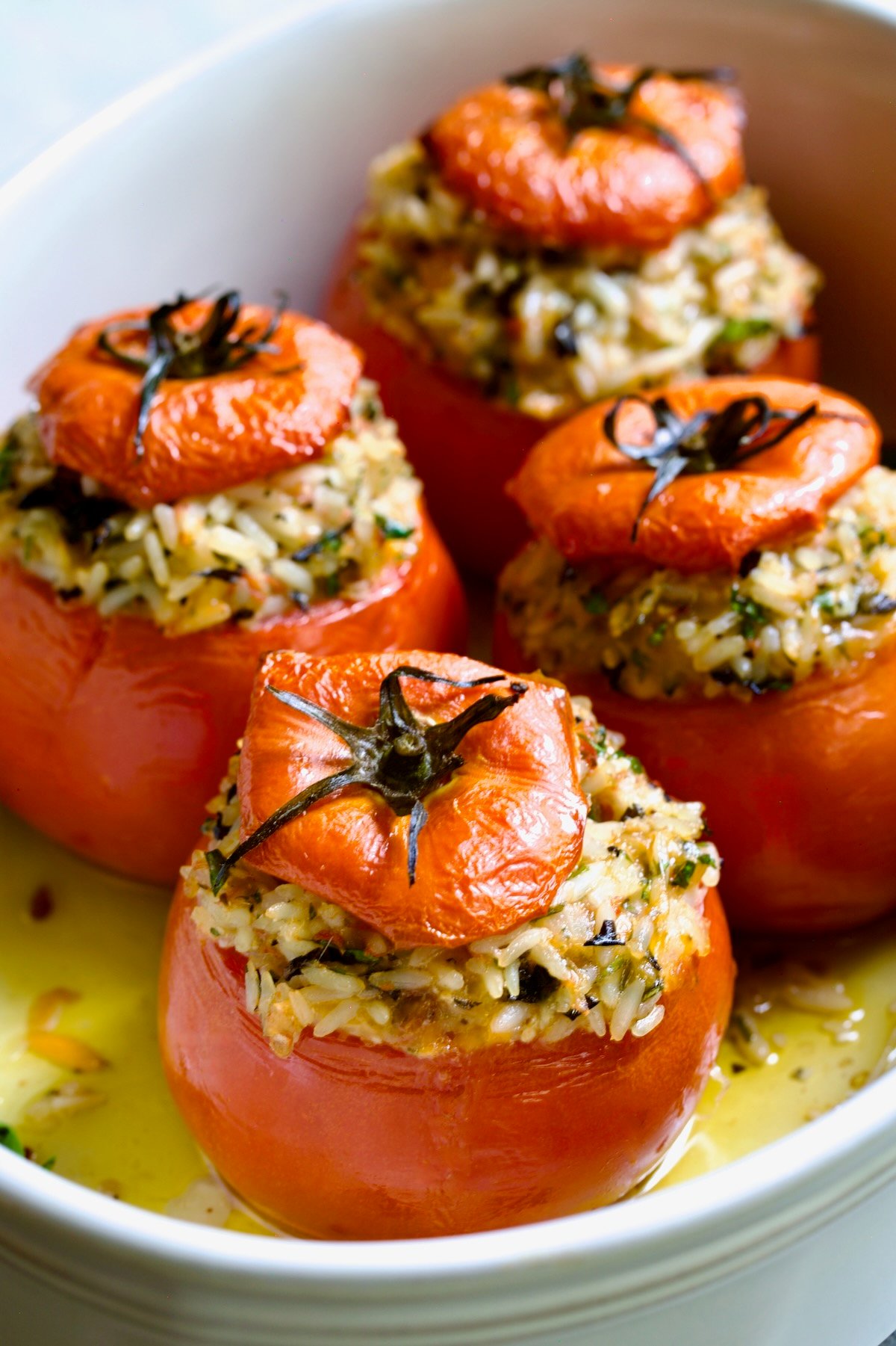Four Cheesy Rice Stuffed Tomatoes in white baking dish.