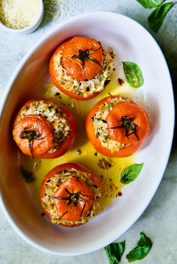 Four Cheesy Rice Stuffed Tomatoes in white oval baking dish.