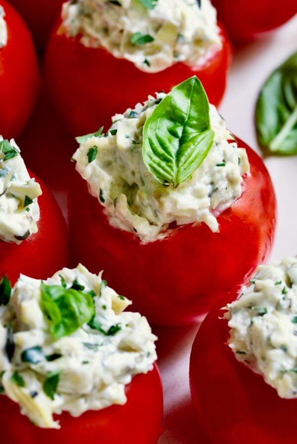 Cream Cheese and Artichoke Stuffed Tomatoes garnished with fresh basil leaves.