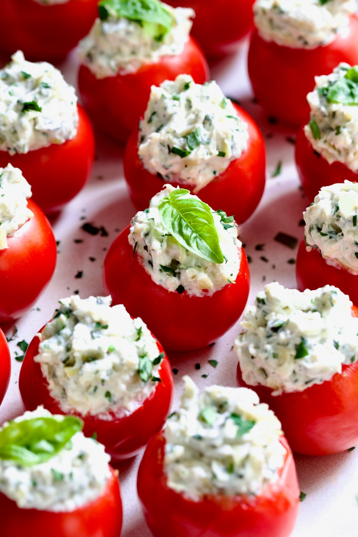 Cream Cheese and Artichoke Stuffed Tomatoes garnished with fresh basil leaves.