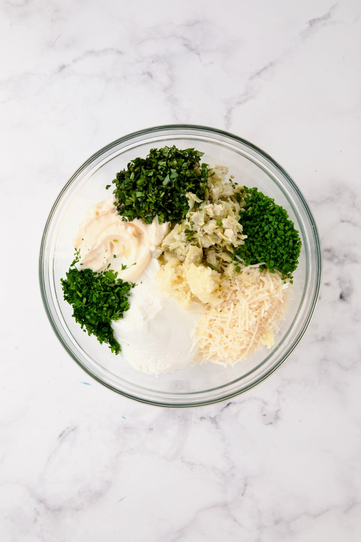 Ingredients for Cream Cheese and Artichoke Stuffed Tomatoes in glass bowl before being mixed together.