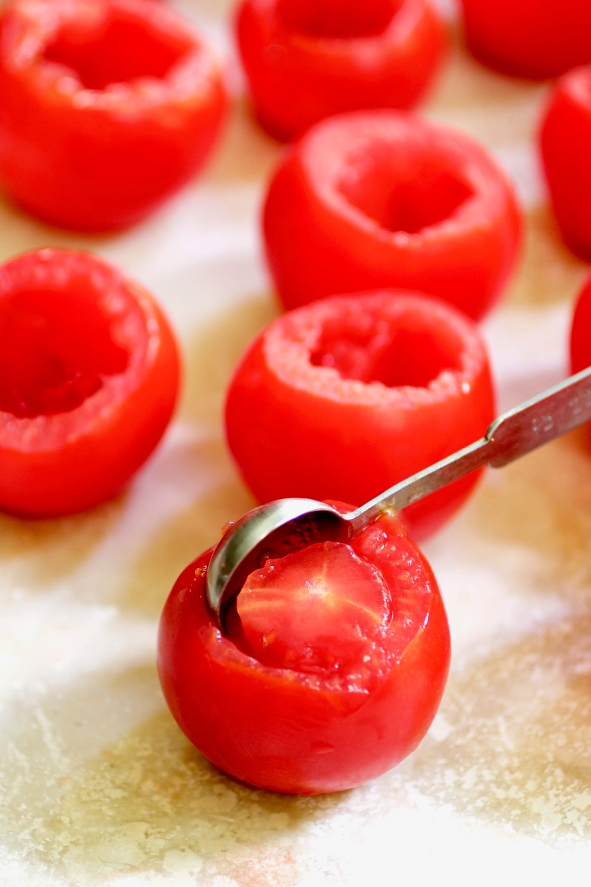 Teaspoon removing the center of Campari tomatoes.