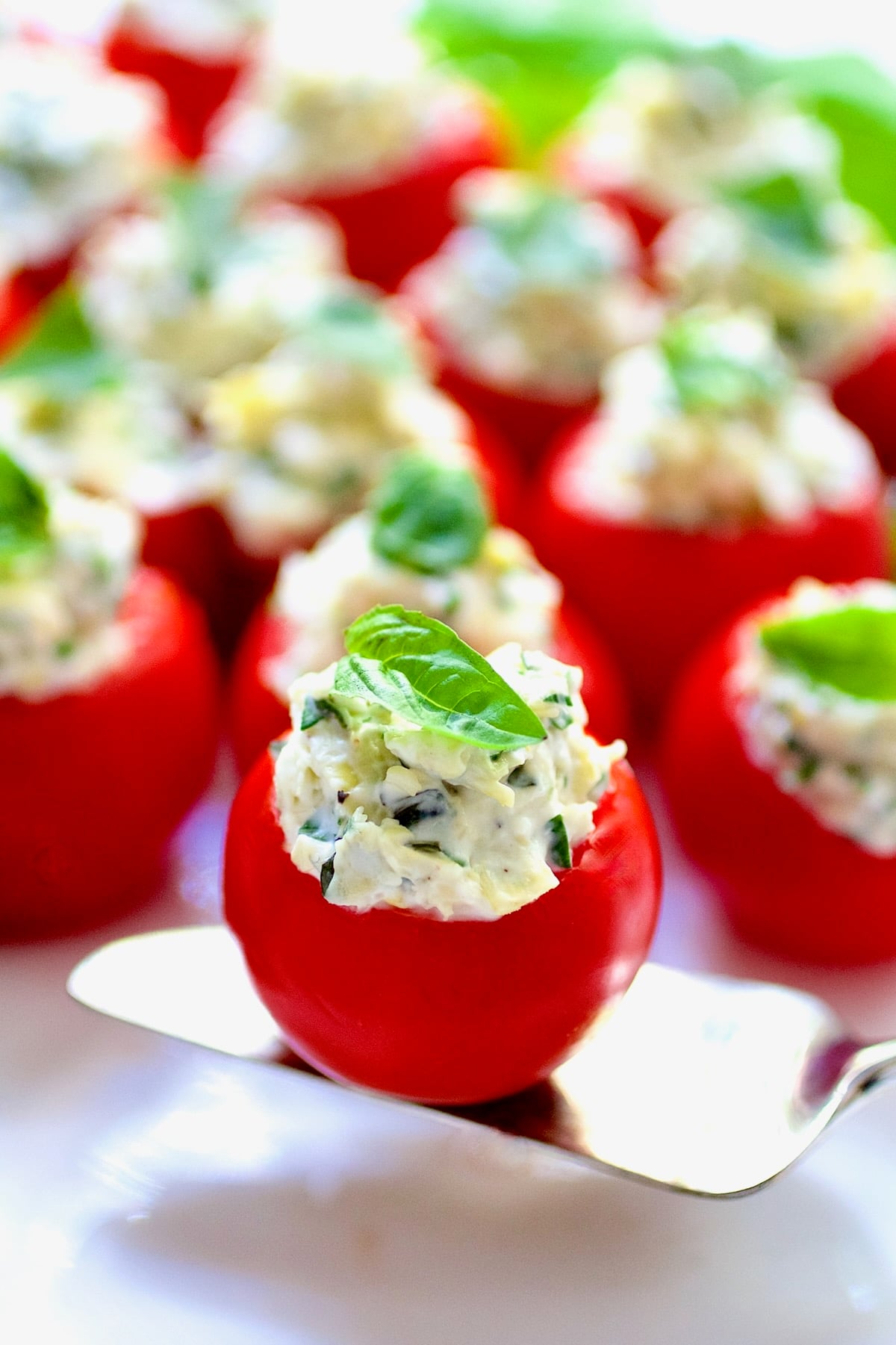 One Cream Cheese and Artichoke Stuffed Tomato on a small silver pie server.