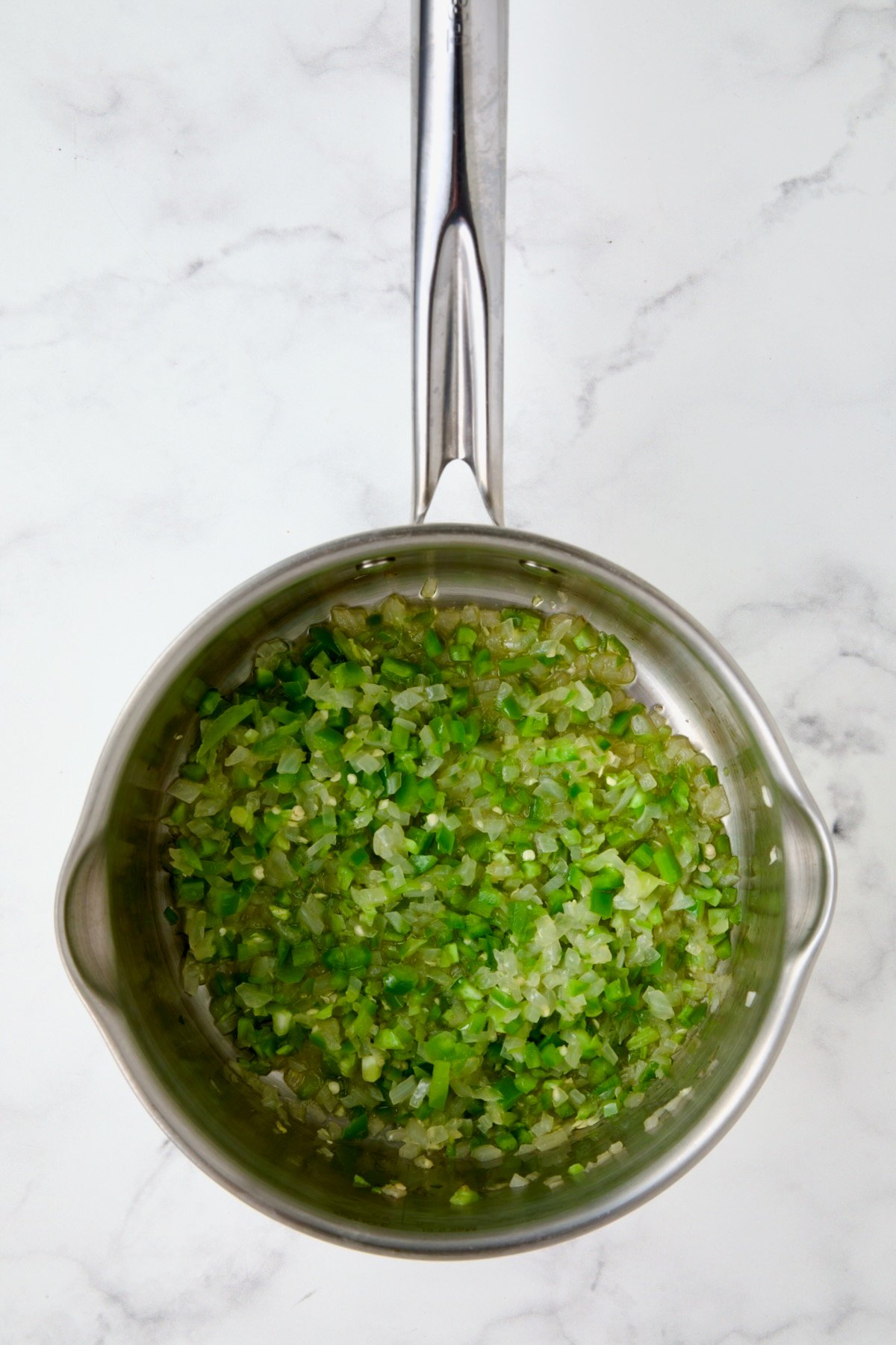 Cooked onion and jalapeno in olive oil in a stainless steel saucepan.
