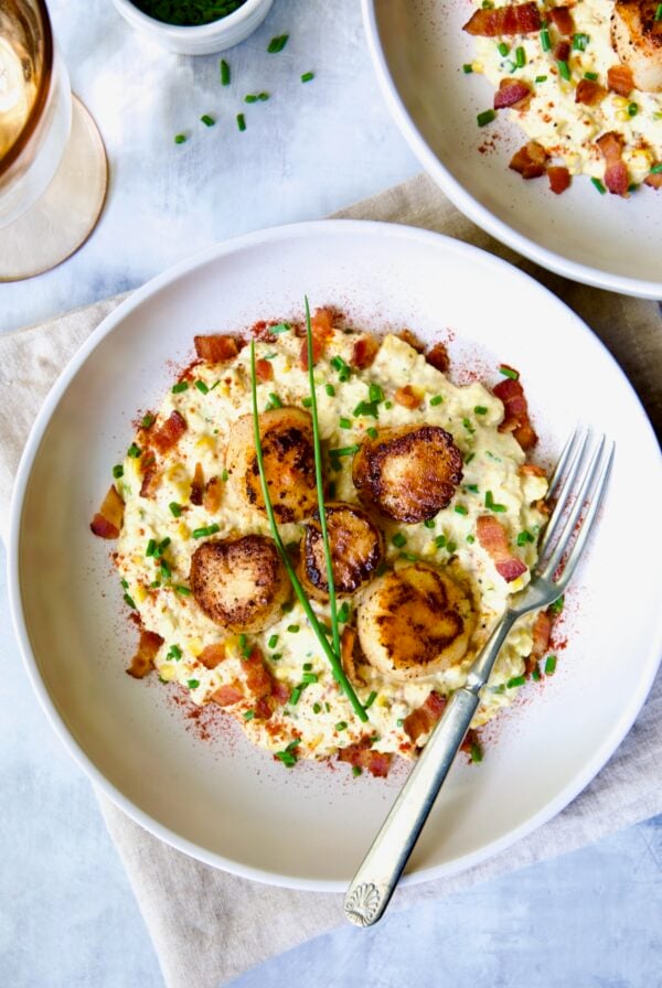 One serving of Seared Sea Scallops with Smoky Sweet Corn Puree on white plate with fork.