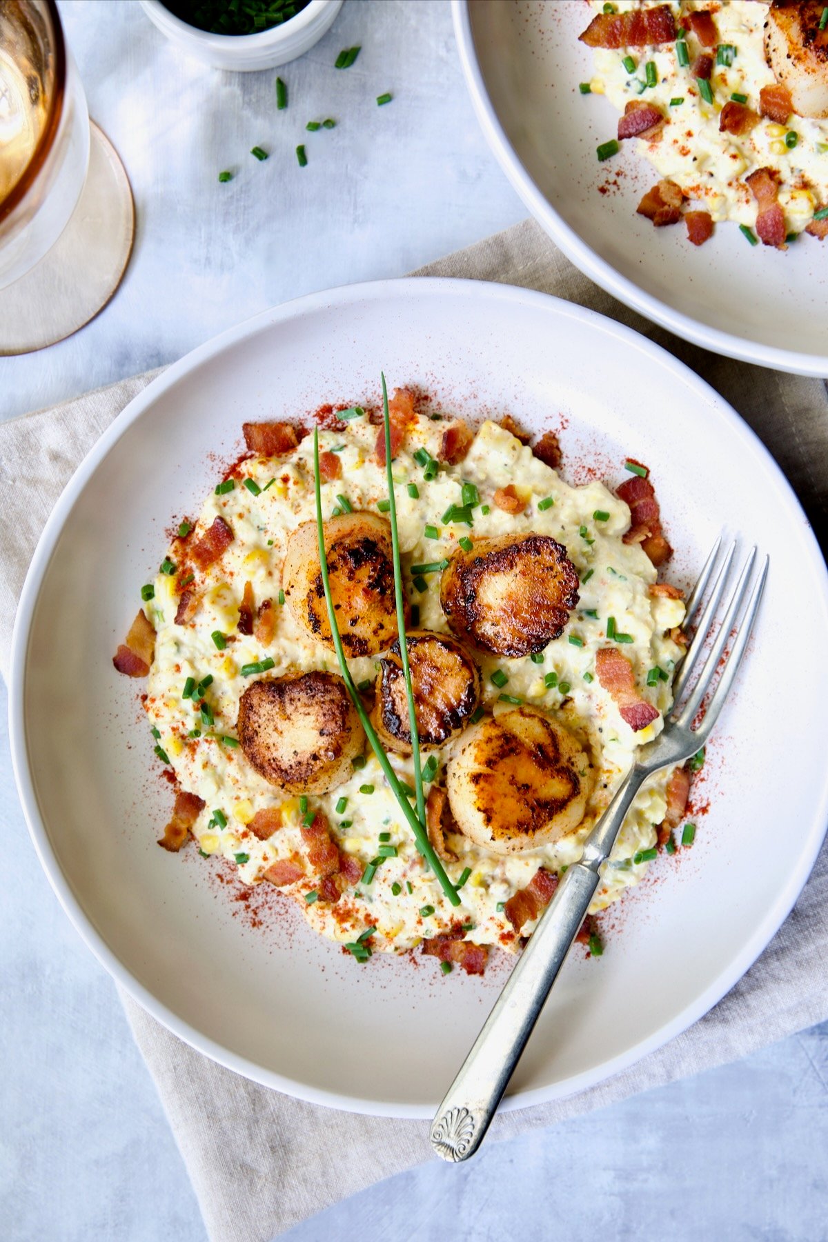 One serving of Seared Sea Scallops with Smoky Sweet Corn Puree on white plate with fork.