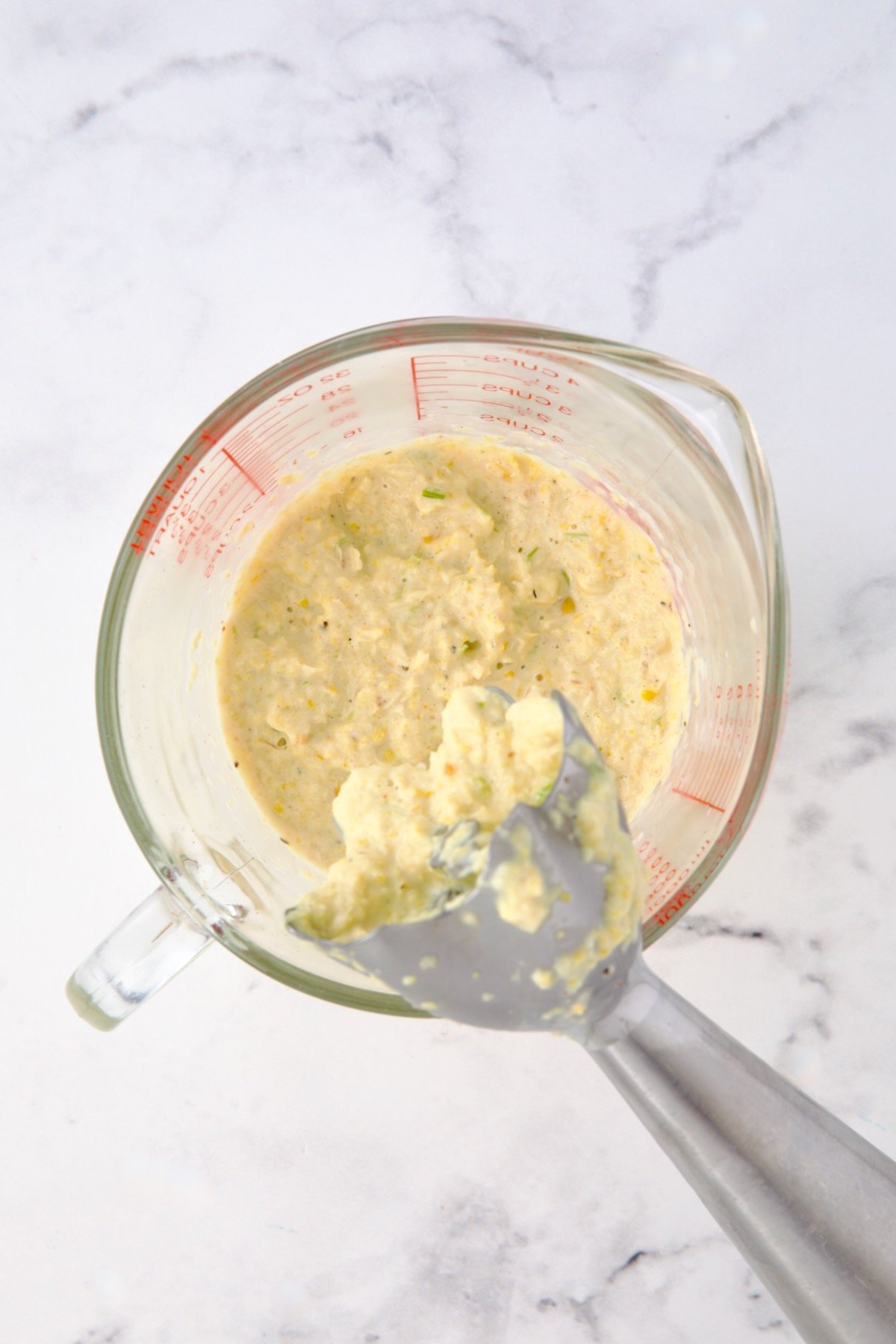 Pureed corn in glass measuring cup.