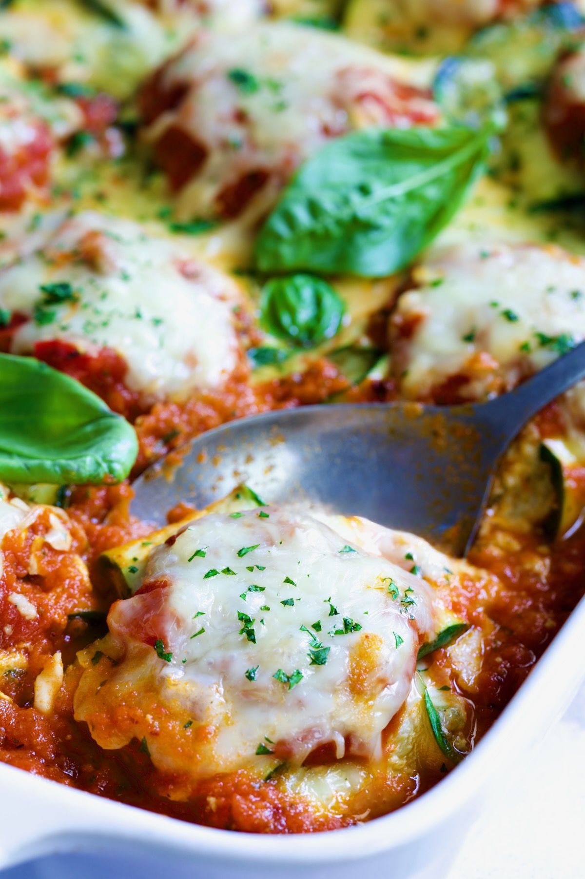 Zucchini Ravioli in white baking dish with serving spoon.