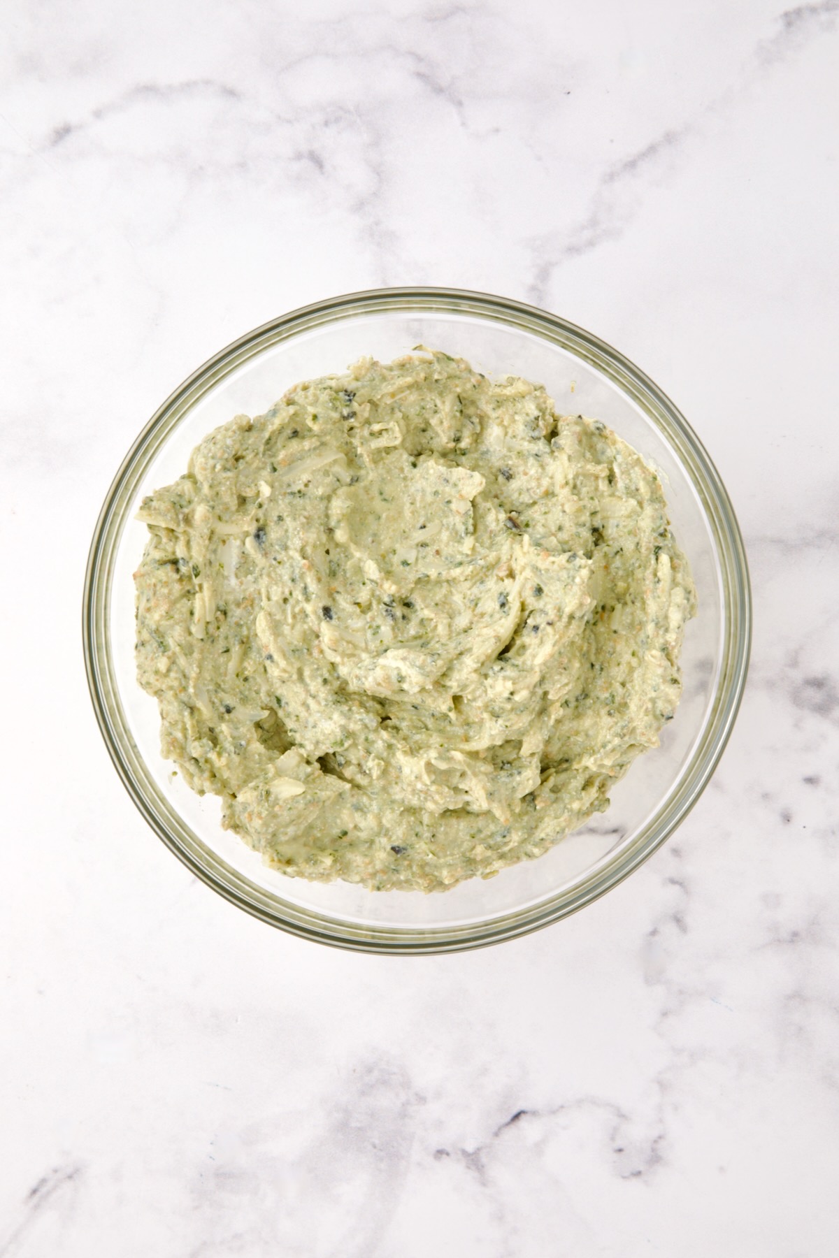 Ricotta pesto filling for ravioli in glass bowl.