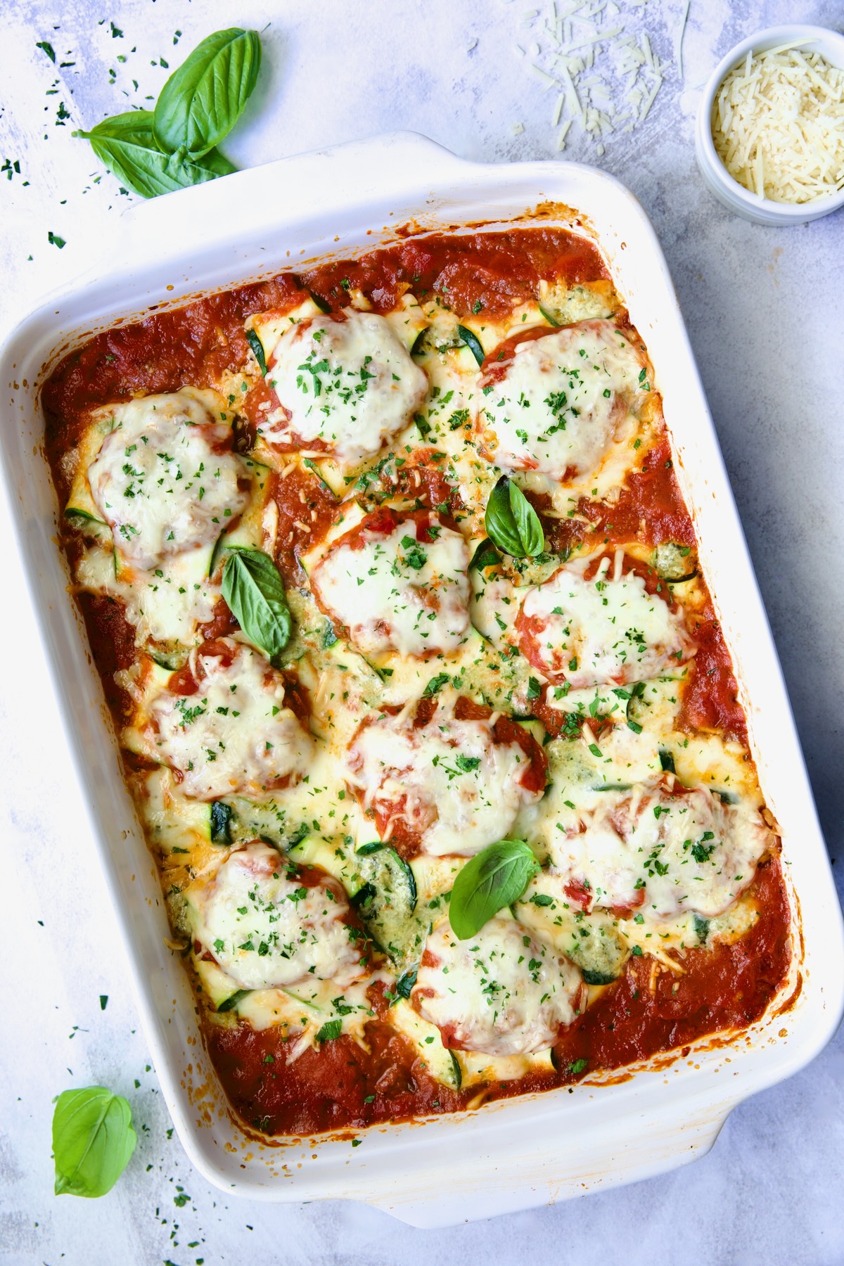 Zucchini Ravioli in white baking dish with serving spoon.