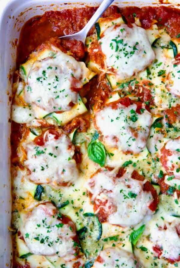 Zucchini Ravioli in white baking dish with serving spoon.