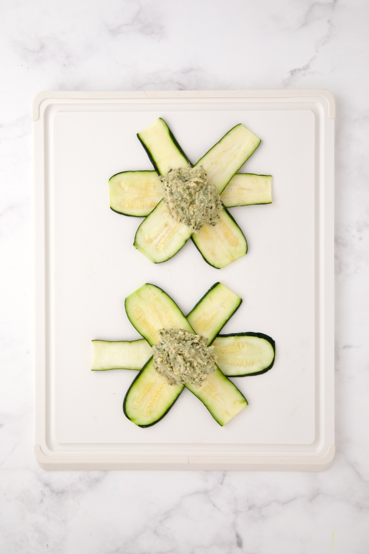 Two sets of zucchini slices in a star pattern with ricotta pesto filling in the center.