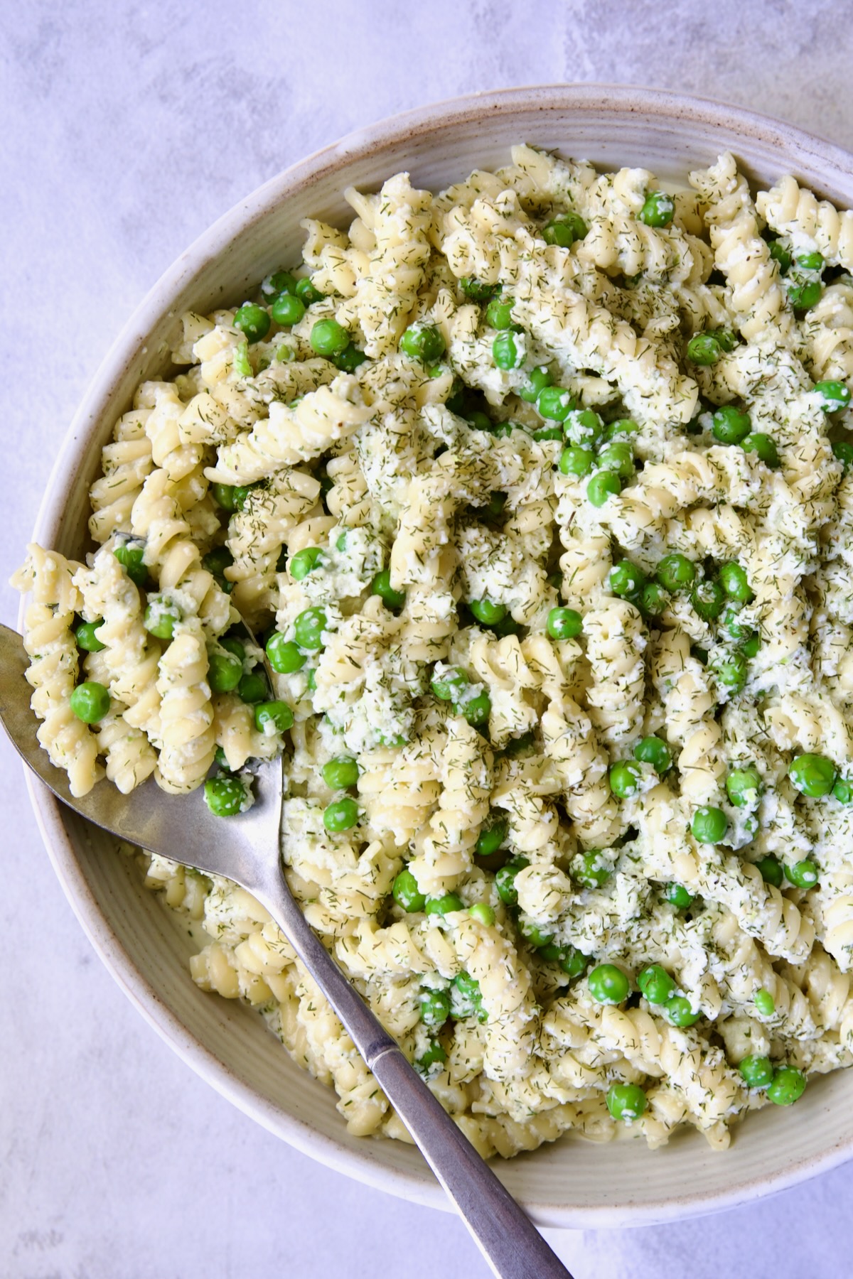 Creamy Cucumber Pasta Salad in white serving bowl with serving spoon.